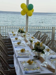 Yalos Restaurant Bar - μακρύ τραπέζι εκδήλωσης με λουλούδια στη βεράντα πάνω από τη θάλασσα